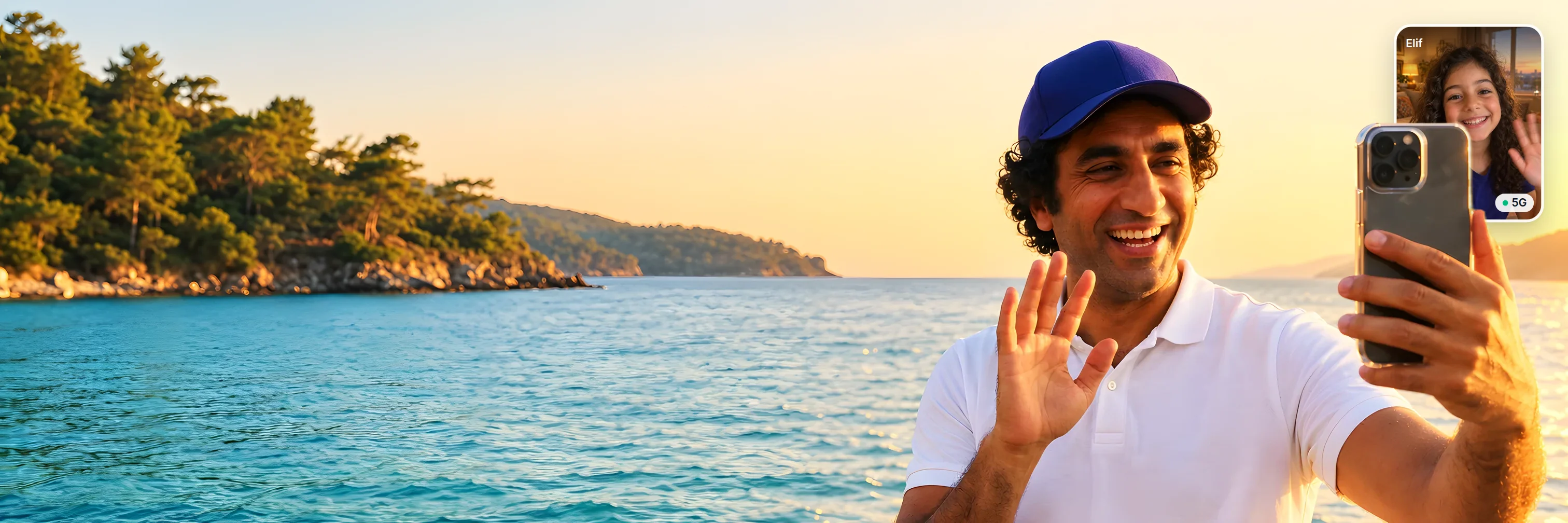 Man in an indigo cap laughing and waving at his phone on a video call with his daughter, standing by the sea on a beach in Türkiye at golden hour